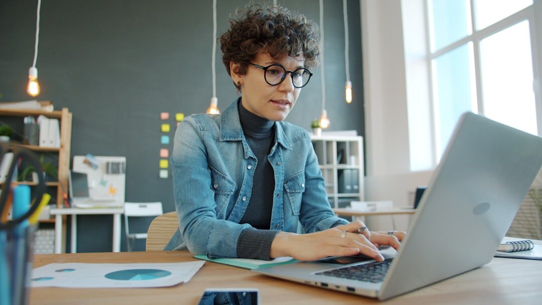 Journalist typing on a laptop in a modern open-plan office
